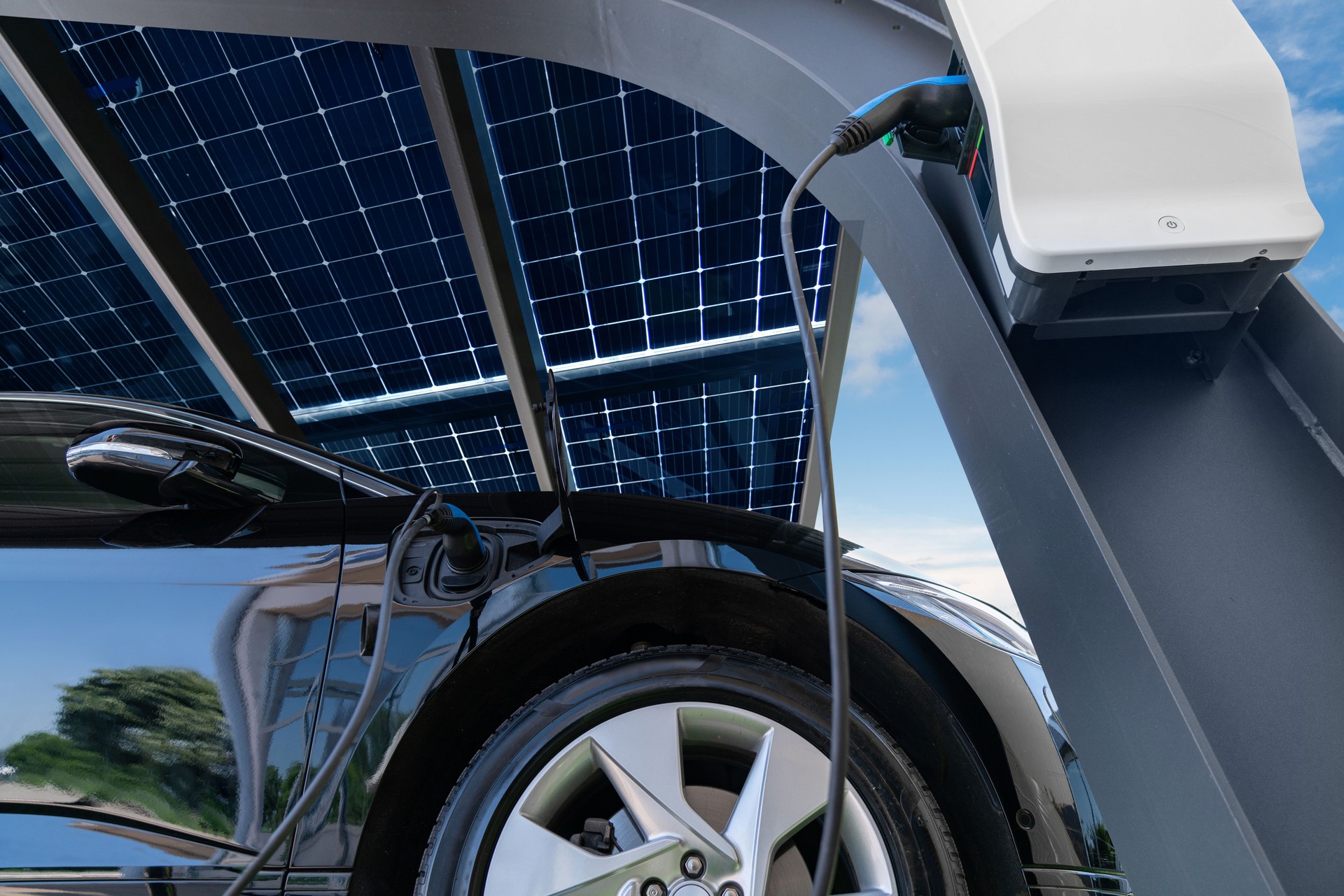 Electric car is charged from a charging station that takes energy from solar panels.
